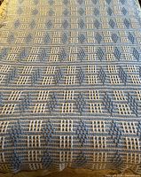 Full view of crocheted blanket laid on bed showing overall pattern and size