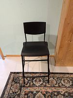 Front view of black IKEA STIG counter stool showing seat, backrest and legs