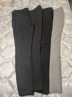 Four pairs dress pants laid out flat displaying colors and overall condition
