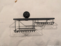 Front view showing entire black metal caddy with suction cup and two baskets