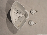 top view of white plastic corner shower caddy with perforated base and two suction cups