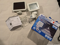 Complete lot showing light fixture, solar panel, hardware, instructions and box