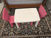 White table with two pink chairs set on rug
