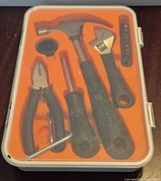 Top view of closed case showing contents: hammer, pliers, screwdriver, adjustable wrench, bit holder, hex key