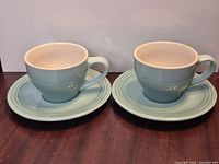 Two Le Creuset cups with matching saucers