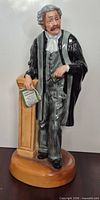 Front view of Royal Doulton "The Lawyer" figurine showing facial detail, attire, lectern, and document