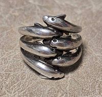 front view of silver ring with five dolphin figures