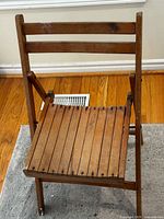 Front view of wood folding chair showing slatted seat and back