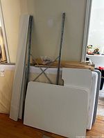 Disassembled white panels, metal cross brace, wooden slats and mattresses leaning against wall