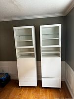 Front view of both white IKEA tall display cabinets side by side