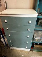 Front view showing four teal drawers with white knobs