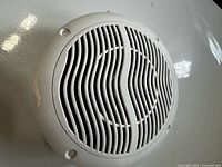 Front view showing white slotted grille and four mounting holes