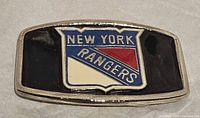 Front view of silver-tone metal belt buckle with New York Rangers crest