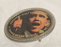 Front view of oval Obama belt buckle showing image and text
