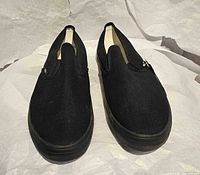 Top view of both black Vans slip-ons showing condition and style