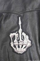front view of skeleton hand patch on leather background