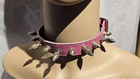 Front view of pink choker on mannequin showing silver-tone cone spikes