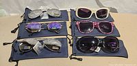 Six pairs of tagged sunglasses displayed on individual navy pouches