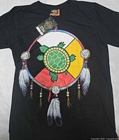 Front view of black T-shirt showing full dreamcatcher turtle graphic and attached hangtag