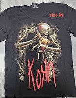 Front view of black Korn graphic T-shirt showing artwork and size label