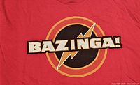 Front design of red Bazinga logo T-shirt showing text and lightning bolt graphic