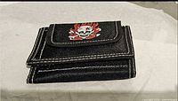 Black denim-style wallet with skull flames graphic on front flap