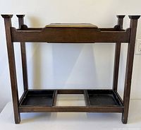Front view of oak umbrella stand showing frame, drip trays, and storage box