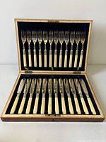 Open oak canteen showing entire 24-piece fish cutlery set