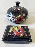 Round and rectangular Moorcroft lidded boxes side by side