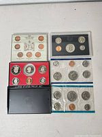 Overview showing proof sets (black and red lenses), Lincoln cent variety board, uncirculated set packs and outer slipcase