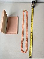 Necklace laid beside tape measure showing 20 in length and jewelry box