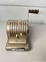 Front view of gold Paymaster S-600 adding machine showing dollar and cents columns, lever, and Paymaster logo