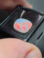 Full view of the fire opal showing cushion cabochon shape and play-of-colour