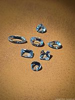 Seven loose aquamarines displayed on neutral background