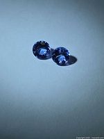 Pair of round tanzanites under direct light