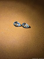 Two pear-cut light blue aquamarine stones on surface