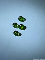 Four vivid green round faceted stones on white background