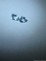 Pair of light blue cushion-cut aquamarines on neutral background