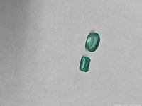 Oval and emerald-cut loose emeralds on neutral background