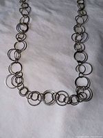 Full view of long silver-tone circle link necklace laid flat showing alternating ring sizes