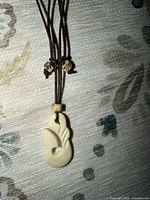 Close-up of carved cream pendant and beads on brown cord