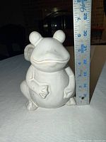 front view of ceramic frog beside ruler showing height