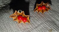 Close-up of one earring showing leaf shape and red berries