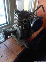 Front view of antique single cylinder engine showing pulley, cylinder fins and mounting base