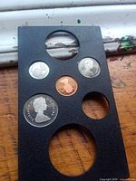 Front of holder showing obverse Queen portraits of four coins and two empty slots