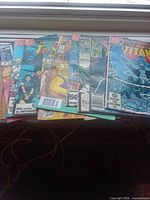 Stack of nine comic books overlapped, showing various titles and 60¢+ cover prices