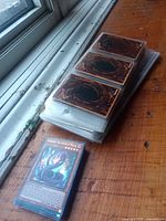 Stack of Yu-Gi-Oh! cards in binder pages next to loose stack