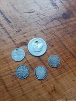5 silver coins arranged on wooden surface