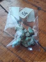 Bag with rough opals labeled 56 on wooden surface