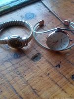 Both wristwatches side by side on wooden surface